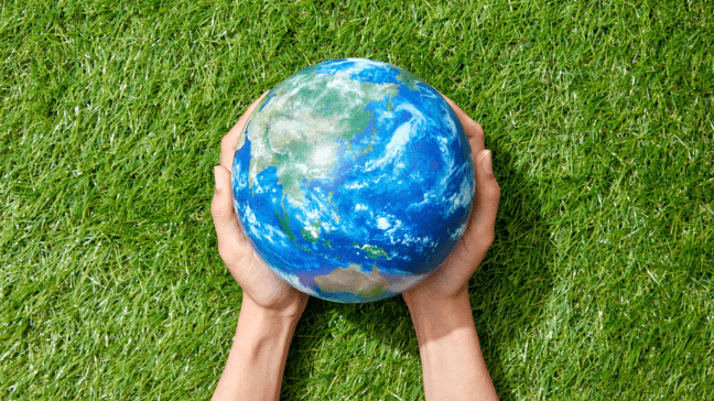 Unas manos cuidan una bola en forma de planeta Tierra